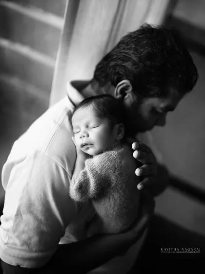 A father holds his sleeping newborn, a quiet moment of connection captured in dramatic black and white. A tribute to the quiet strength of new dads.