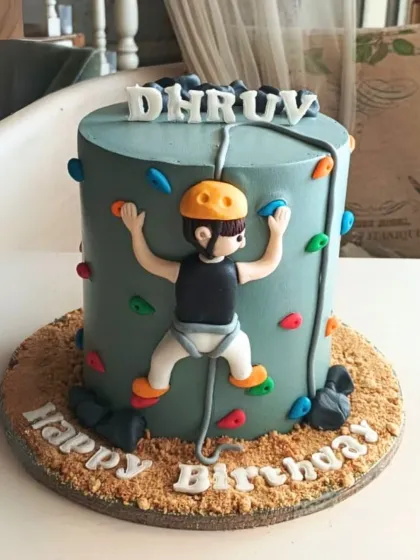 An adventurous rock climbing cake with a fondant climber scaling the side, complete with colorful holds and a textured base.