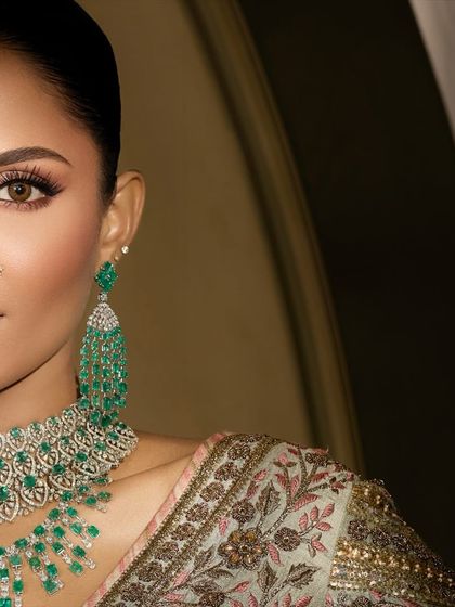 A close-up of this modern bride's look, focusing on the sharp winged liner and flawless skin that allows the stunning emerald jewelry to truly stand out.