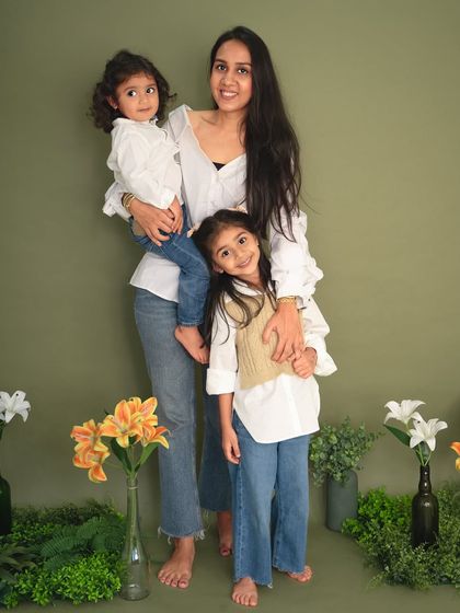 A mother stands proudly with her two daughters. This full-length portrait from our Mother's Day sessions captures a beautiful moment between them.