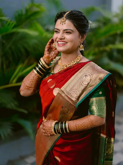 A candid portrait of the bride, Pranjali, her joyful smile captured as she adjusts her hair on her wedding day.