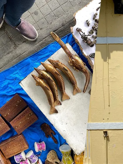 A street vendor's stall with carved wooden fish and boxes, a glimpse of local craftsmanship.