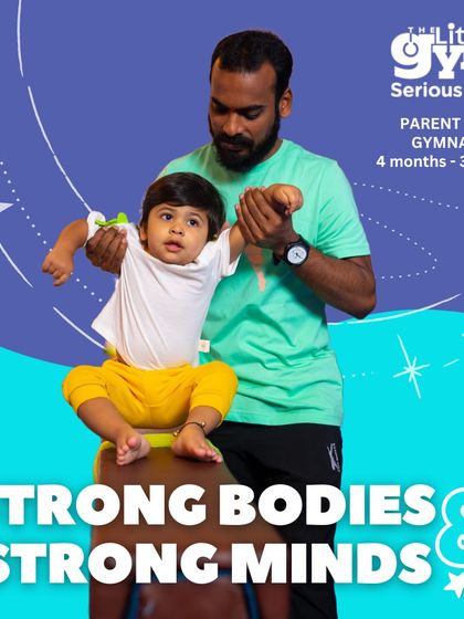 In our parent-child program, we guide you and your toddler through activities that build core skills. Here, an instructor helps a father support his child in a balancing exercise, which is crucial for developing stability and body awareness from a very early age.