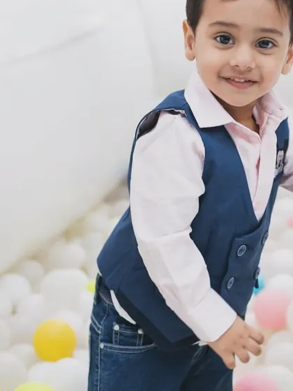 A happy child in the ball pit of our white bounce castle. The pit is filled with clean, colorful balls for sensory play.