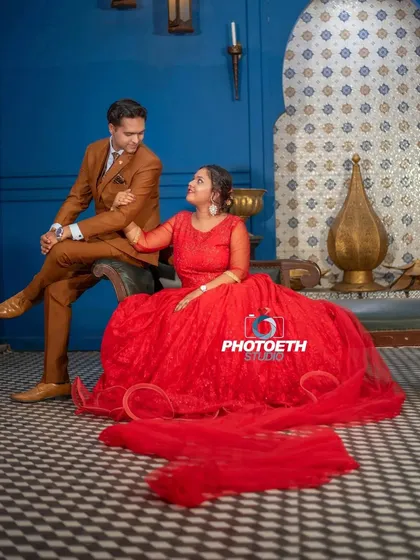 A vibrant and stylish indoor shot. The contrast between the bride's red gown and the rich blue and black checkered floor creates a visually striking image.