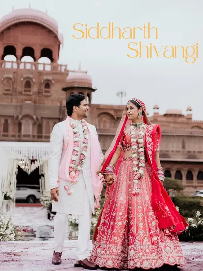 A classic wedding portrait of the couple holding hands in front of the majestic Laxmi Niwas Palace, a perfect blend of love and royalty.