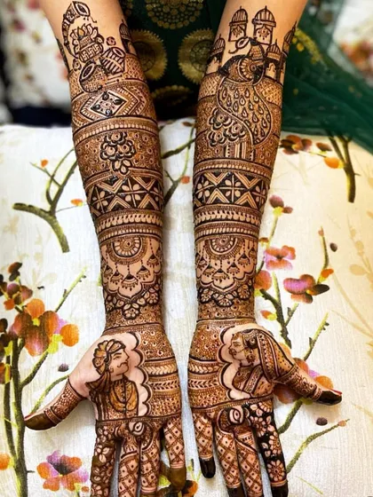 A unique take on portrait mehandi, with the bride and groom figures placed on the thumbs. The arms feature peacock and jharokha designs.