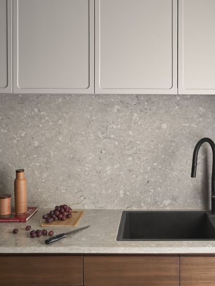 A detail of the kitchen sink area, where natural elements like grapes and a wooden board complement the terrazzo countertop. It's a space designed for real life.