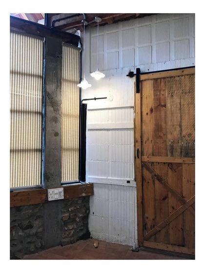 Another view of the farmhouse interior, focusing on the interplay of materials. The rough texture of the stone foundation contrasts with the smooth, white paneled wall and the warm tones of the wooden barn door.