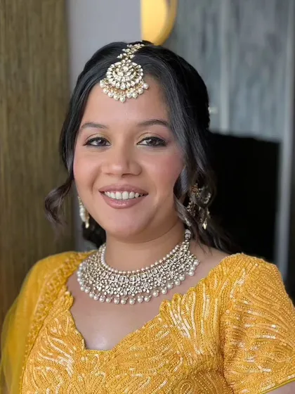 A second look for the same client, this time in a vibrant yellow outfit. The makeup is soft and natural, with a focus on glowing skin.