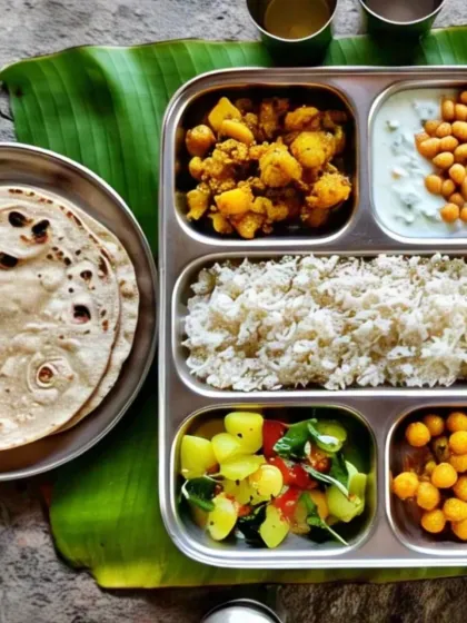 This compartmentalized thali keeps every dish distinct and flavorful. It contains rice, aloo sabzi, chana, raita, a fresh salad, and rotis, offering a well-rounded meal.