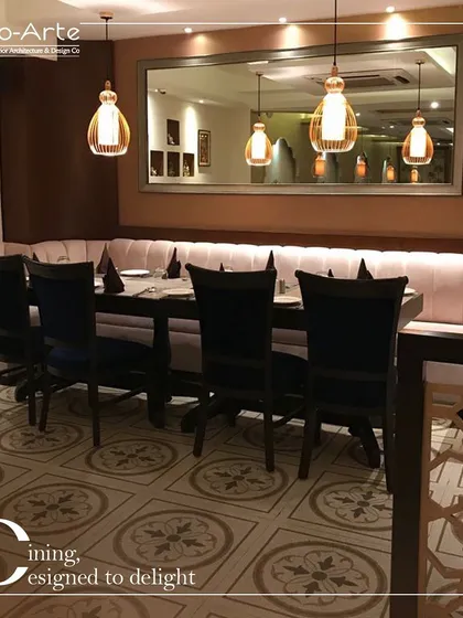 Dining designed to delight at Café Hera Fehri. This seating arrangement combines a long, comfortable banquette with elegant chairs and patterned floor tiles, creating a space that is both contemporary and timeless.