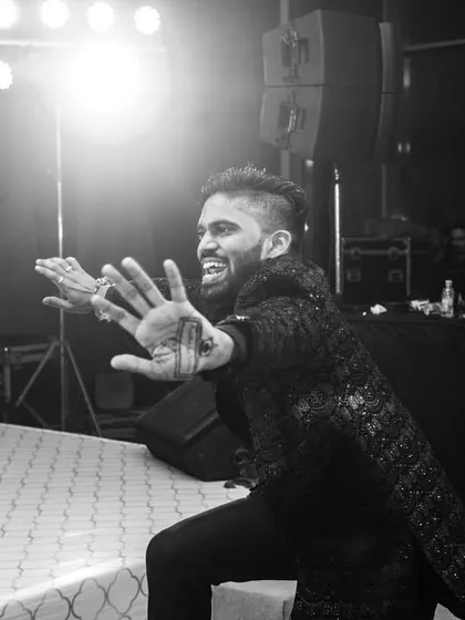 A candid, black and white shot of a guest showing off his dance moves on the Sangeet stage.
