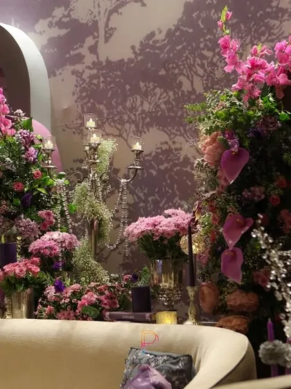 A detailed shot of the floral arrangements behind the sofa, showcasing the mix of vibrant pinks and purples, crystal elements, and candelabras that brought the space to life.