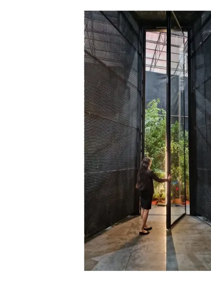 A visitor opens the large pivoting door of the Durall Pavilion. The act of entering the space is a transition from the busy exhibition hall into a calm, contemplative environment.