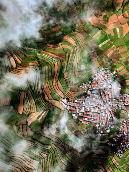 A top-down photograph of Poombarai Village, Kodaikanal, with clouds partially obscuring the view, adding a layer of mystery and depth.