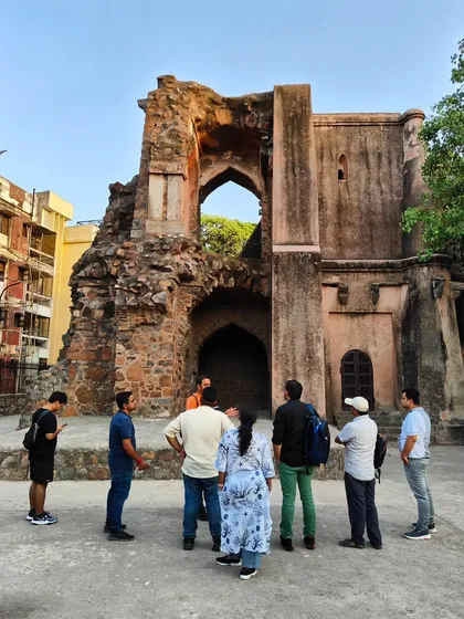A guide explains the history of a ruined gateway in Mehrauli. Our walks are interactive history lessons where you can see and touch the past.
