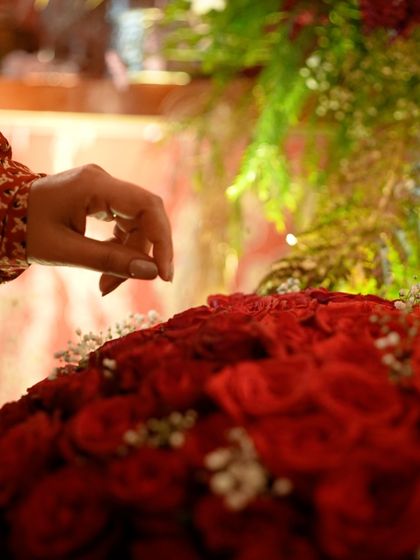 A close-up of a hand placing a single red rose, symbolizing the care and attention that goes into every floral arrangement.
