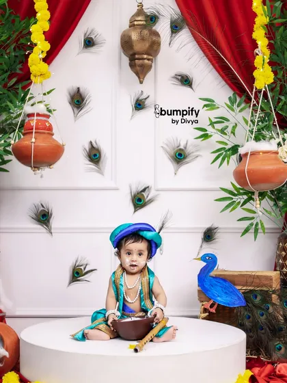 A full view of one of my Janmashtami setups, featuring rich red curtains, peacock feathers, and hanging matkis to create a vibrant and festive backdrop for your little Kanha.