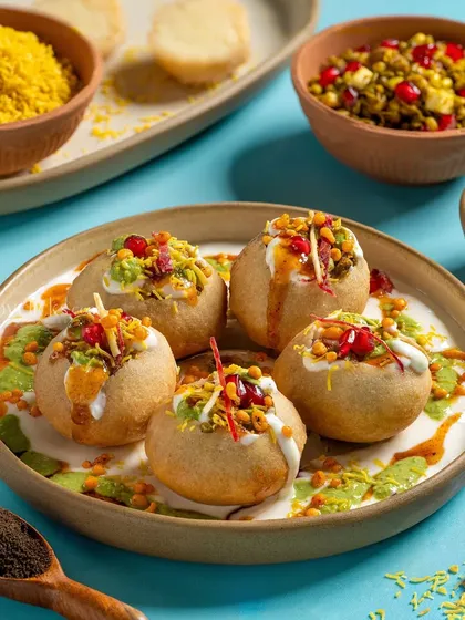 Dahi Puri from Gulab Sweets, with a vibrant blue background that makes the colors of the chutneys and pomegranate seeds pop.
