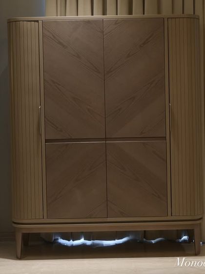 When closed, the bar cabinet is a beautiful piece of standalone furniture. The combination of fluted sides and a chevron veneer pattern on the doors adds texture and a modern, sophisticated touch to the living space.
