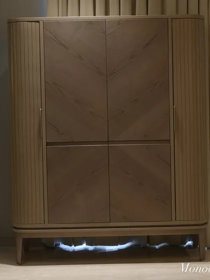 When closed, the bar cabinet is a beautiful piece of standalone furniture. The combination of fluted sides and a chevron veneer pattern on the doors adds texture and a modern, sophisticated touch to the living space.