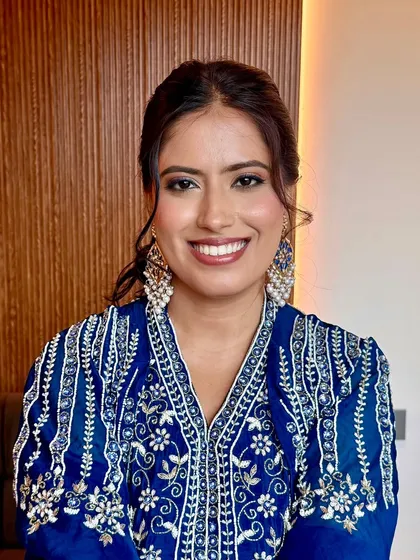 A smiling portrait of the bride. The soft glam makeup enhances her features without looking heavy, perfect for a daytime event.