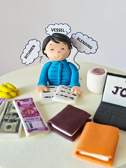 A close-up of a personalized cake for a friend, featuring fondant toppers that represent his job in the shipping industry, with terms like "Vessel," "Bitumen," and "Blending."