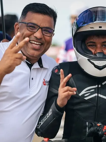 The joy of achievement. A young rider in full gear shares a celebratory moment with a coach, both flashing victory signs. This captures the personal connection and shared success that defines our team spirit.