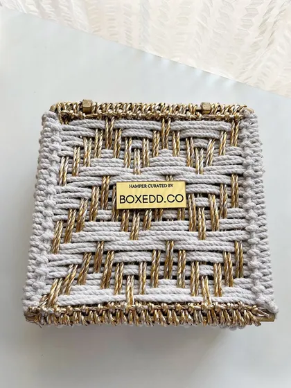 A close-up of our custom-branded woven box. The metallic plate with "HAMPER CURATED BY BOXEDD.CO" signifies our attention to detail and quality craftsmanship.