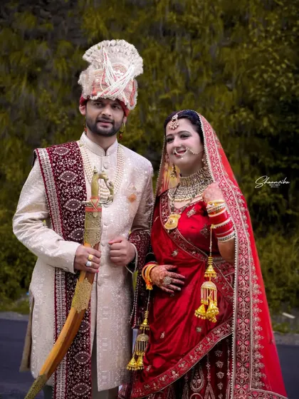 A joyful wedding portrait of the couple. The bride's happy expression and the groom's proud stance make this a perfect memory of their special day.