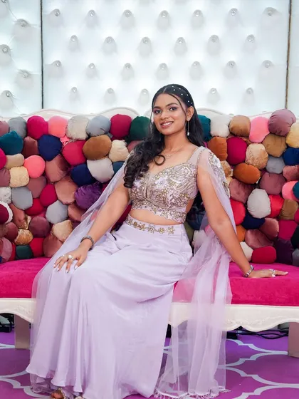 This client is ready for her event, seated on a colorful couch. Her soft glam makeup and pearl-studded hairband create a look that is both trendy and timeless.