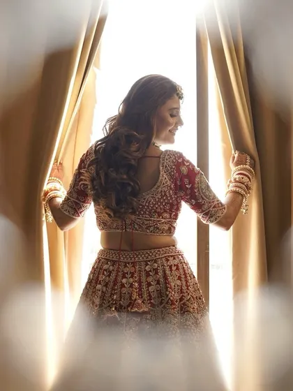 A beautiful silhouette of the bride against the light, showing off the fit of her blouse and the soft curls in her hair.