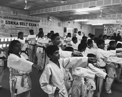A class of young students practices their blocks in unison during a belt exam. This synchronized movement showcases their discipline and focus.