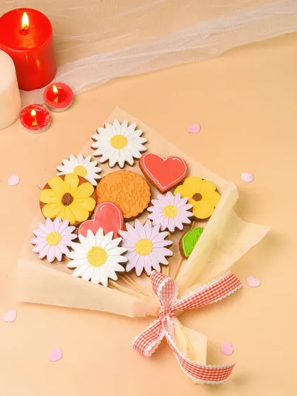 A cookie bouquet wrapped with a ribbon, styled with romantic candles for a special occasion.