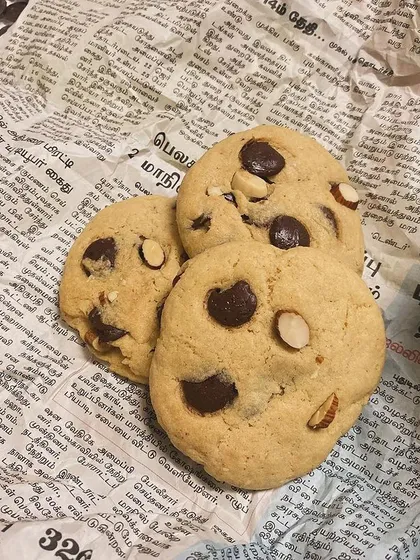 Our classic chocolate chip and almond cookies, fresh from the oven. The newspaper background gives it a rustic, homemade feel.