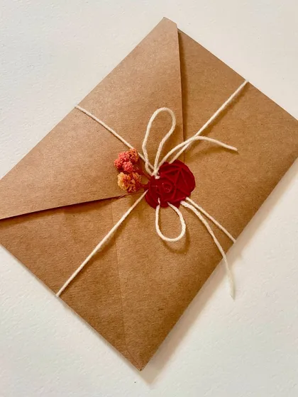 The final presentation of a custom letter, sealed with twine and a red wax stamp with dried flowers. This is how it arrives, ready to be gifted.