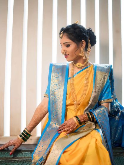 An elegant seated portrait of the bride, showcasing her beautiful yellow and blue saree.