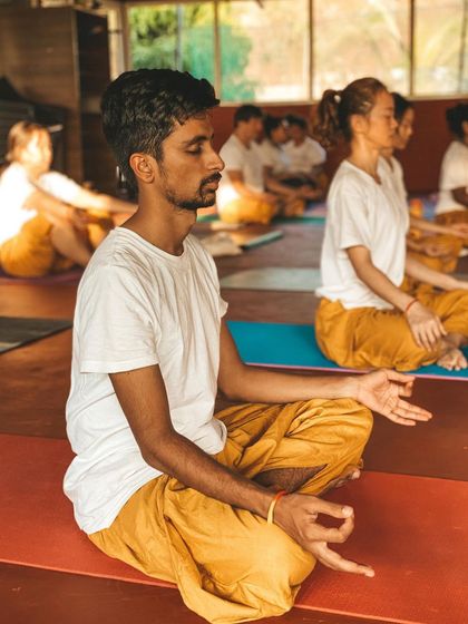 A student sits in Padmasana (Lotus Pose) with Chin Mudra, the gesture of consciousness. This is the classic posture for meditation, creating a stable and balanced seat for deep inner exploration.