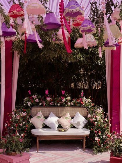 The seating area for a Rajasthani-themed Mehendi, featuring a floral-draped sofa and hanging lampshades that add a quirky and colorful touch to the decor.