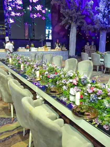 A long, mirrored table adorned with a lush floral runner, creating a breathtaking setting for a formal sit-down dinner.