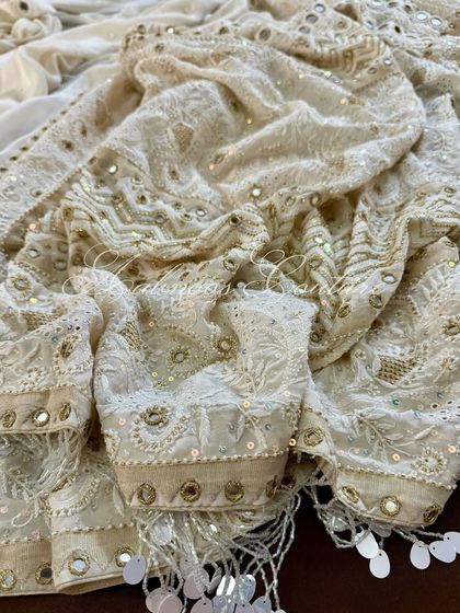 A close-up of the draped fabric, showing the intricate details of the embroidery and mirrorwork.