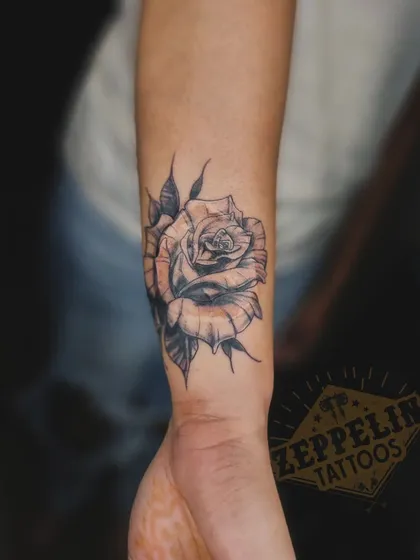 A beautifully shaded black and grey rose tattoo designed to cover a burn scar on the wrist.