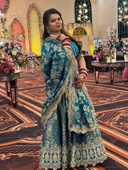A full-length view of the teal brocade lehenga. The heavy gold work on the border and dupatta gives it a luxurious feel, making it a great rental for a special occasion.