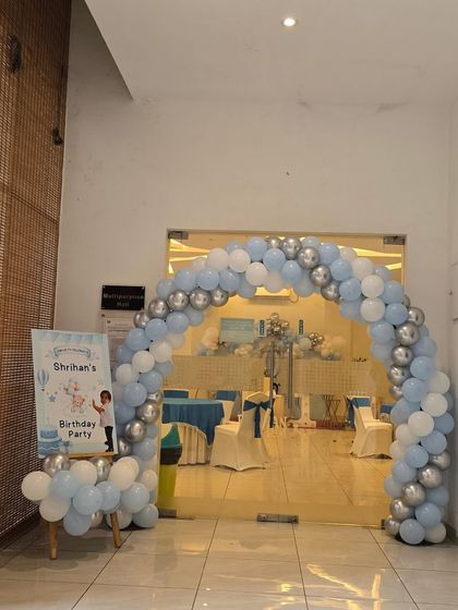 A blue and silver balloon arch at the entrance to a hot air balloon themed party.