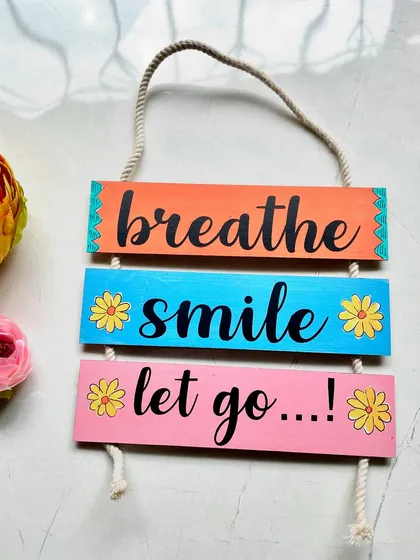 A daily reminder to 'breathe, smile, let go'. This colorful wall hanging is a simple way to bring a moment of peace into your day.