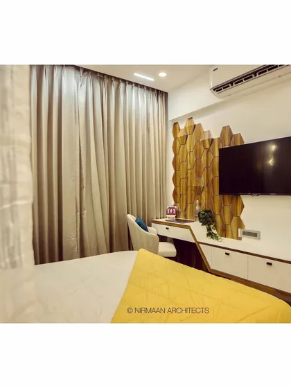 A view of the daughter's bedroom at Bhagwati Greens, showing the cozy bed and the modern study area against the hexagonal wood wall.