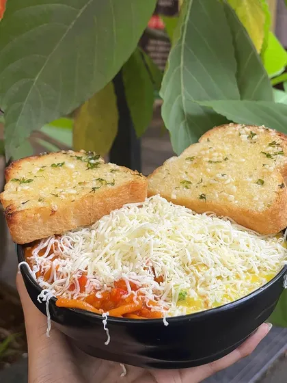 My Pasta & Pasta dish, featuring a combination of red and white sauce pasta, topped with a mountain of cheese and served with garlic bread.