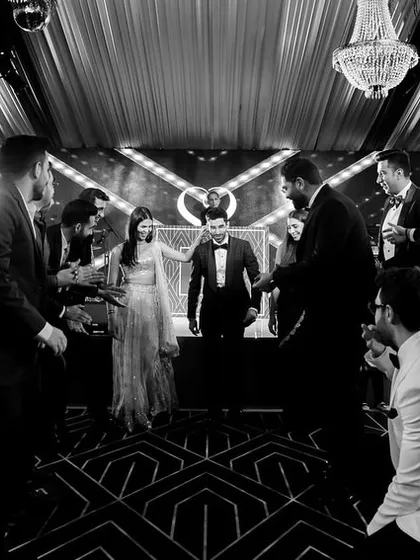 A black and white shot capturing the groom's entry, surrounded by his groomsmen, creating a cool and stylish moment.