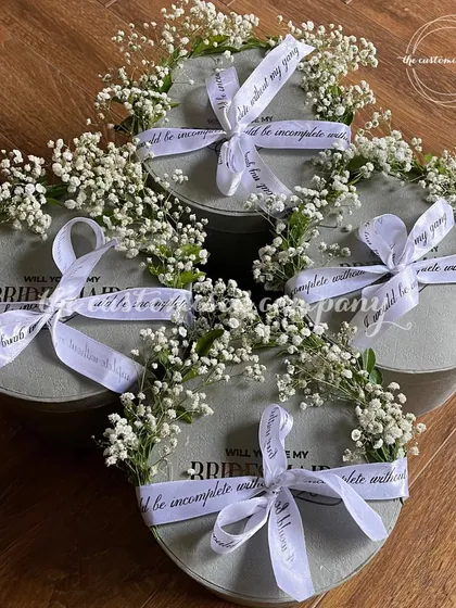 A beautiful way to ask, "Will you be my bridesmaid?". These elegant proposal boxes are adorned with fresh baby's breath and a custom ribbon, creating a truly special moment for your bride tribe.